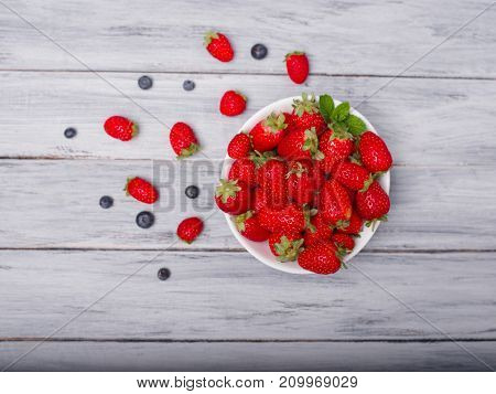 Fresh ripe fruits on a gray wooden table. Sweety red strawberries summer fruits on a gray background. Close-up of strawberry. Food concept.