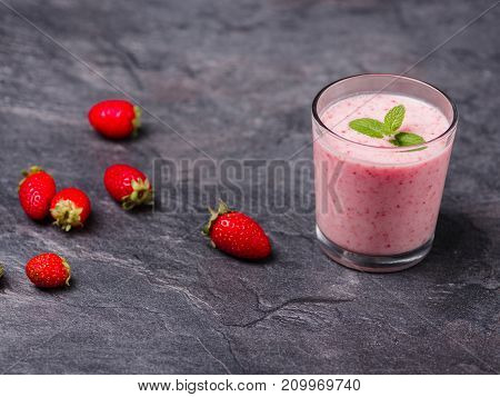 Tasty sweet strawberries and fruits yogurt in a glass on a gray marble background. Healthy organic drink. Copy space. Food concept.
