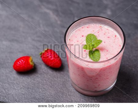 Tasty sweet strawberries and fruits yogurt in a glass on a gray marble background. Healthy organic drink. Copy space. Close-up of drink. Food concept.