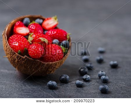 Fresh ripe fruits on a gray background. Sweety red strawberries and blueberries on a dark background. Copy space. Close-up of fruits. Food concept.