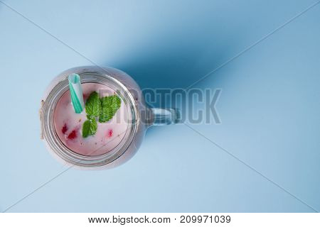 Tasty sweet strawberries and fruits yogurt in mason jar on a blue background. Healthy organic drink. Copy space. Close-up of drink. Food concept.