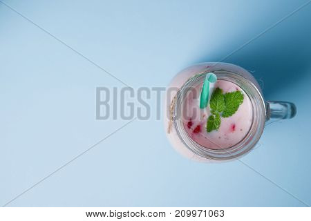 Tasty sweet strawberries and fruits yogurt in mason jar on a blue background. Healthy organic drink. Copy space. Close-up of drink. Food concept.