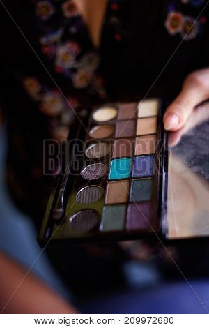 Cosmetic beauty procedures and makeover concept. Woman holds makeup professional palette. Make-up applying