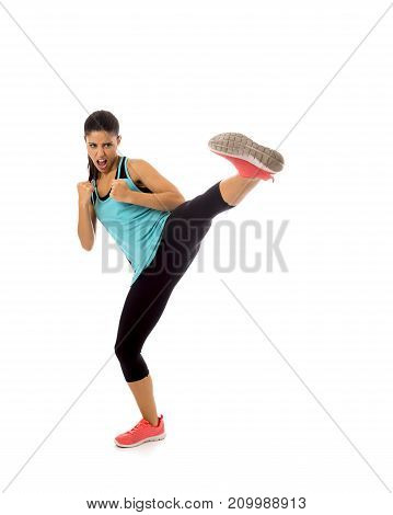 young attractive and furious latin sport woman in fight and kick boxing training workout throwing aggressive kick attack isolated on white background in gym exercise and personal defense concept