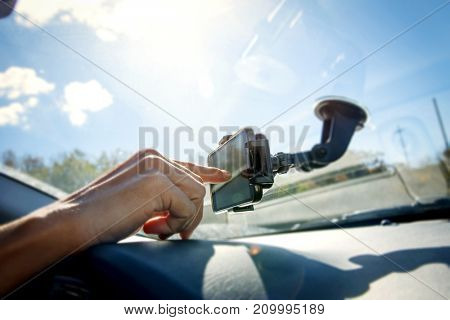 closeup of a young caucasian man using a smartphone as a GPS mounted in a holder stuck in the windscreen of a car