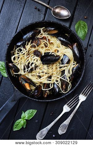 Seafood Dish. Rustic Style Spagheti With Mussels And Basil In Cast Iron Pan On Dark Background Top V