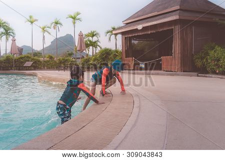 Two Asian Siblings In Playing Together In Water Aqua Park Pool.