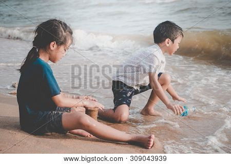 Children Is Cleaning Up Garbage On The Beach For Enviromental Clean Up Concept