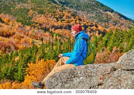 Backpacker man hiking at Artist's Bluff in autumn. Fall colours in Franconia Notch State Park. White Mountain National Forest, New Hampshire, USA