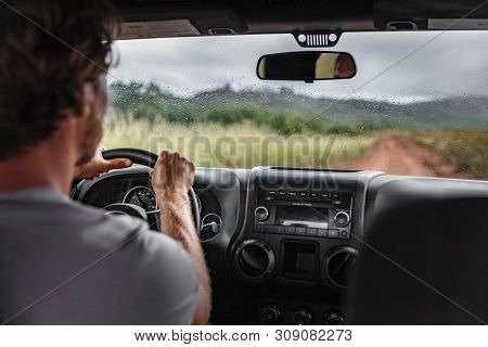 Man driver driving off road trail path with 4x4 car on adventure trip travel holiday. Hawaii drive in the rain bad weather.