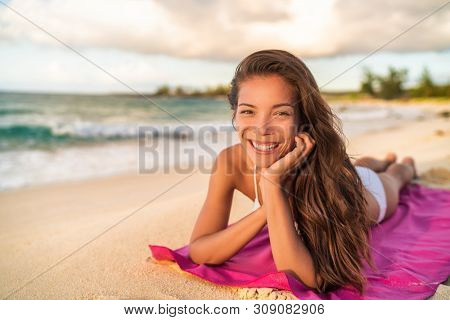 Happy Asian bikini wwoman model relaxing on summer vacation lying on beach towel, Hawaii travel.