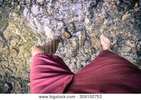Hiking Outdoors In The Forest: Cut Out Of Male Barefoot Feet In A Shallow River, Fresh Water
