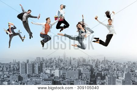 Happy Office Workers Jumping And Dancing In Casual Clothes Or Suit With Folders Above The City. Ball
