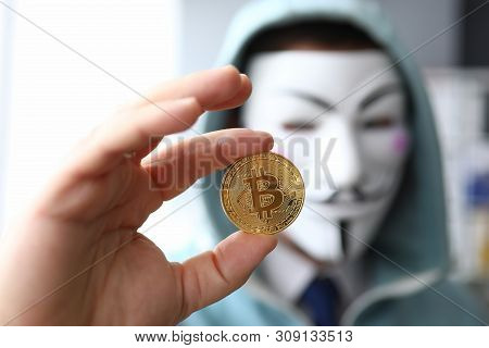 Minsk, Belarus, June, 2019: Hacker Wear Anonymus Mask Hold Bitcoin In Hand Illustrative Editorial