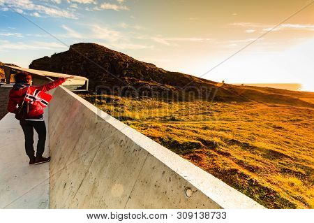 Tourist Woman With Norwegian Flag Enjoying Sea Coast View From Bukkekjerka Rest Stop Area On Andoya 