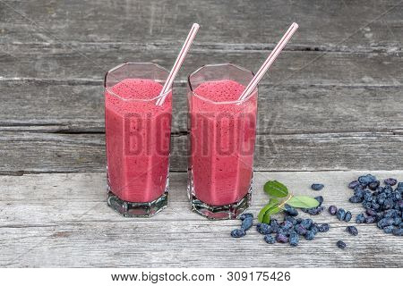 Two Transparent Glasses With Plastic Tubes With Drinking Smoothie From Fresh Wild Honeysuckle And Gr