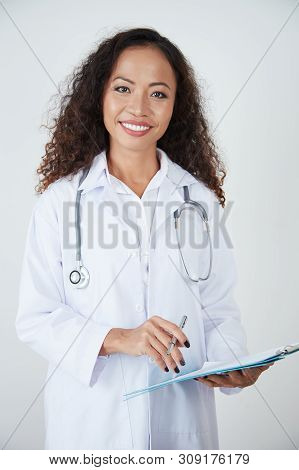 Positive Pretty Positive General Pratitioner Writing Prescription In Document And Smiling At Camera