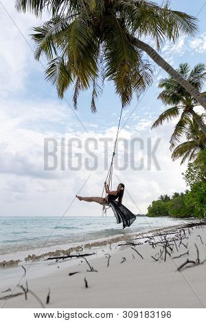 A Young Girl Riding On A Swing. Swing Suspended On The Palpe Above The Water