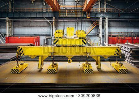 Overhead Crane With Magnetic Grippers Lifting Steel Sheets.