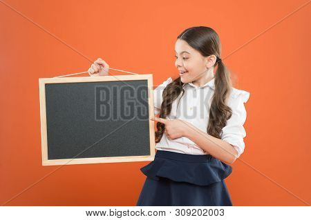 Look At This. Cheerful School Girl With Blackboard. Happy Pupil In School Uniform. Copy Space. Comme