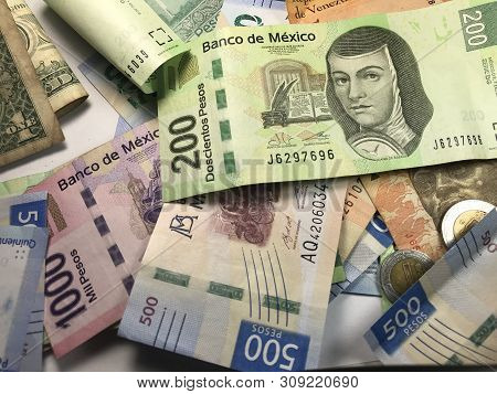 Many Mixed Mexican Peso Bills Spread Over A Wooden Desk