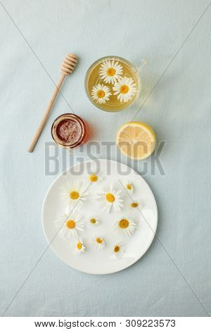 Chamomile Flowers And Chamomile Tea. Chamomile Tea In Glass Teacup With Flowers, Honey And Lemon, To