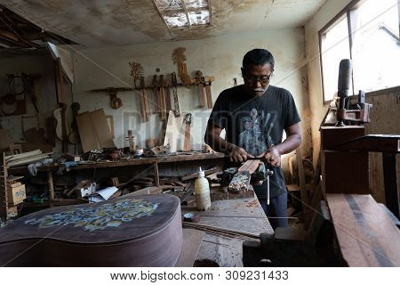 Gianyar,bali/indonesia-may 30 2019: A Guitar Craftsman Is Measuring And Make Sure It Is A Precision