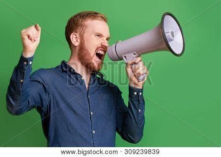 Emotional Young Bearded Propagandist Shouting In Loudspeaker, Isolated On Green