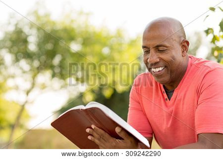 African American Man Praying And Reading The Bible.