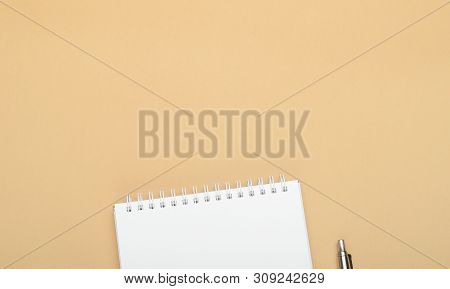 White Notebook With Steel Pen On A Brown Background. Office, Save Space, Mock Up, Template, Top View