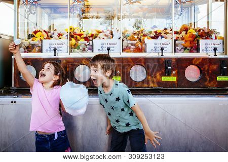 Photo Of A Brother And Sister Eating A Big Cotton Candy At An Amusement Park.