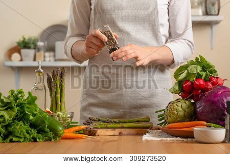 Close-up, Chef Peppers Asparagus, With Vegetables On A Light Background. A Concept Of Losing Healthy