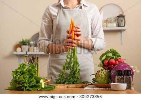Chef Is Holding A Fresh Carrot. The Concept Of Losing Healthy And Wholesome Food, Detox, Vegan Eatin