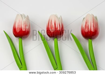 Red Wooden Tulips With Green Stems And Leaves On A White Background, Ornament Background Pattern. Ar