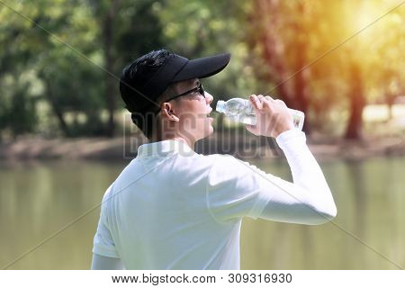 Golfer Man Drinking Of Fresh Water With Bottle While Thirsty And Tired. Young Men Wearing White Shir