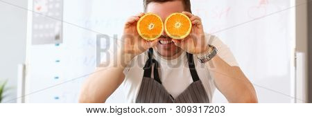 Man Holds Halves Of Cut Orange As Eye Glasses Portrait Background Concept