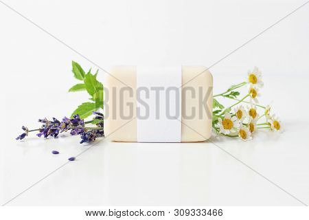 Closeup Of Hand Made Herbal Soap Bar In Blank Paper Label Package. Mint Leaves, Lavender And Feverfe