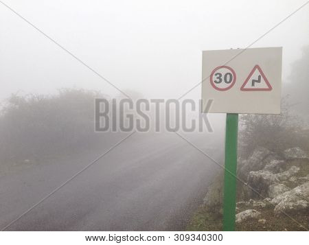 Metal Pole With Traffic Signal Advice Danger Signal Of Curves At Mountain Road In The Fog