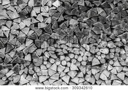 Background Of Splitted, Dried And Stacked Firewood. Bunch Of Wood. Black And White Photo.