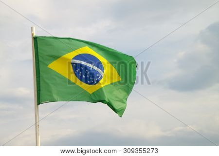 Brazilian Flag On A Blue Sky With Clouds Background