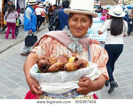 Indigenous Woman Holds Basket With Prepared Traditional Dishes Of Ecuadorian Sierra - Cuy Asado Or G