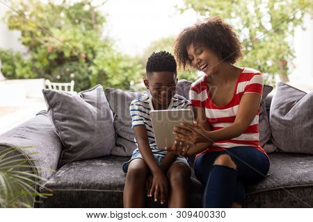 Front view of African american Mother and son using digital tablet on a sofa in living room at home