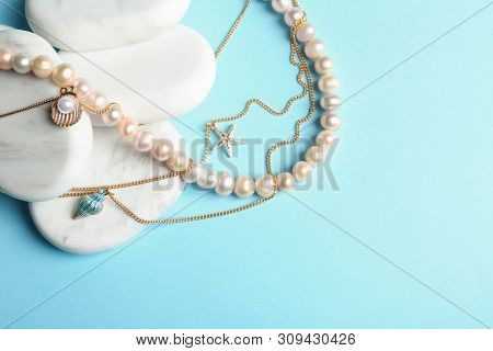White Marble Stones With Elegant Jewelry On Light Blue Background, Top View. Space For Text
