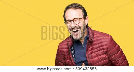 Middle age handsome man wearing glasses and winter coat Smiling and laughing hard out loud because funny crazy joke. Happy expression.