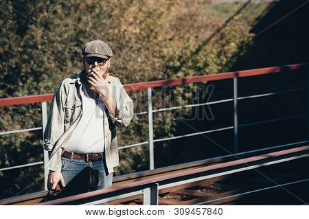 Bluesman With Guitar Case Smokes Cigarette On Railroad. Blues Musician With Cigarette On Railway. Co
