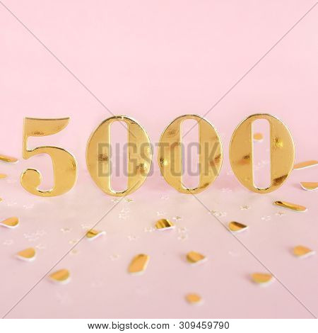 The Number 5000 In Golden Numbers On A Pink Background And Golden Confetti. Space For Text.