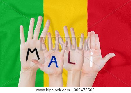 Inscription Mali On The Children's Hands Against The Background Of A Waving Flag Of The Mali