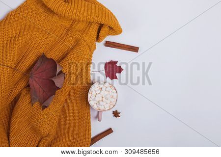 Creative Autumn Composition With Warm Knitted Sweater, Yllow Leaves And Cocoa With Marshmllows