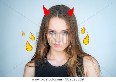Angry Cute Devil. Fashion Portrait Of A Beautiful Young Woman Posing Over White Background. Close Up