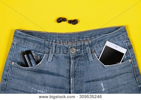 Top View Of Wireless Headphones, Jeans, Charger And Smartphone In Its Pocket On Yellow Background